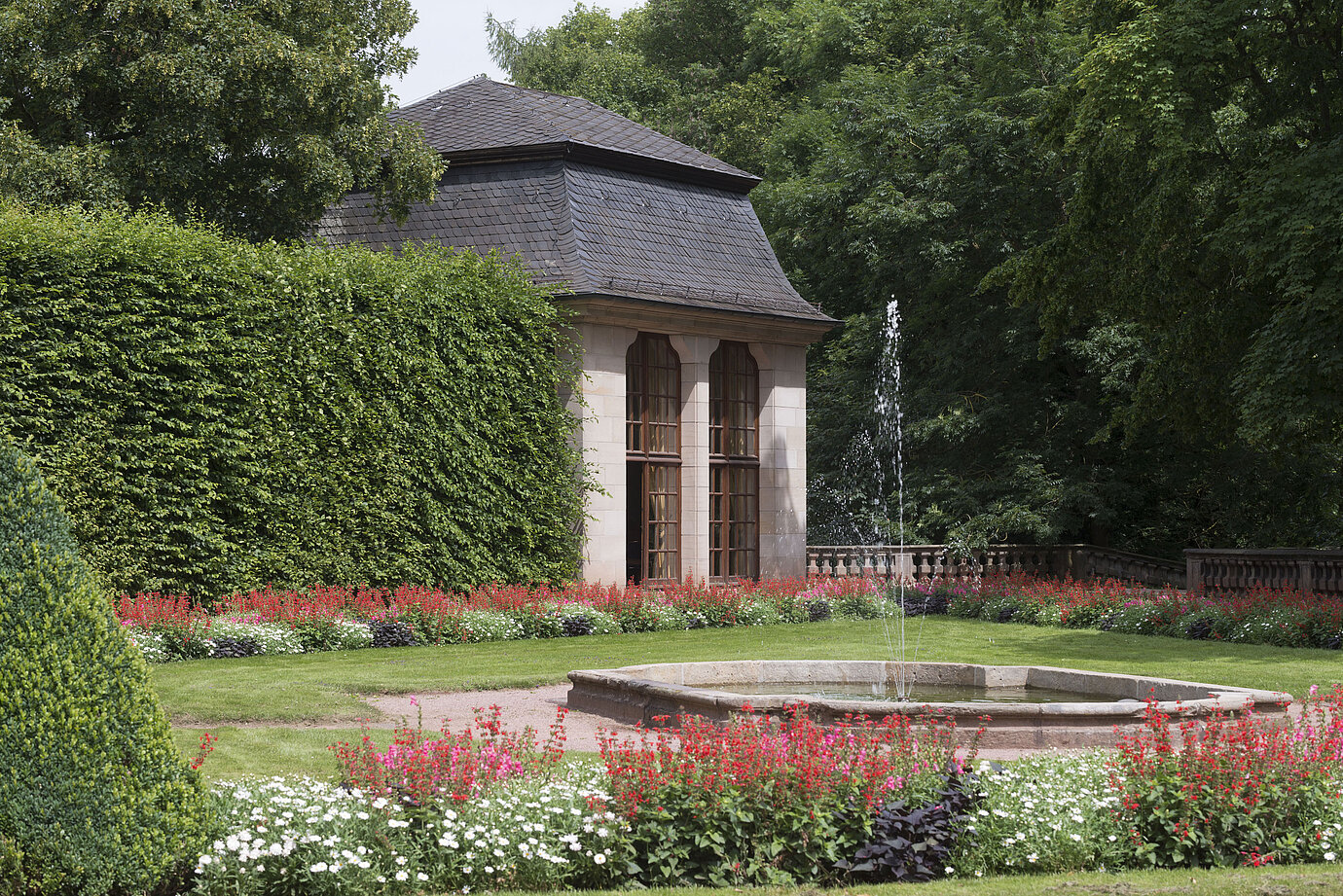 Pavillon historique dans le jardin fleuri du Maritim Hotel Fulda avec fontaine et jeu d'eau.