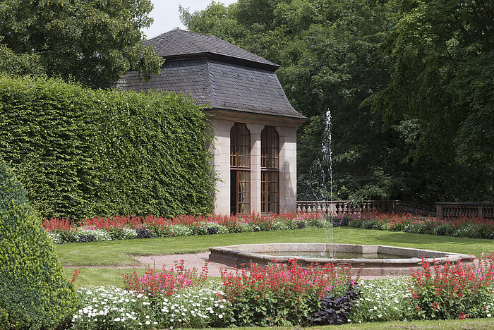 Pavillon historique dans le jardin fleuri du Maritim Hotel Fulda avec fontaine et jeu d'eau.