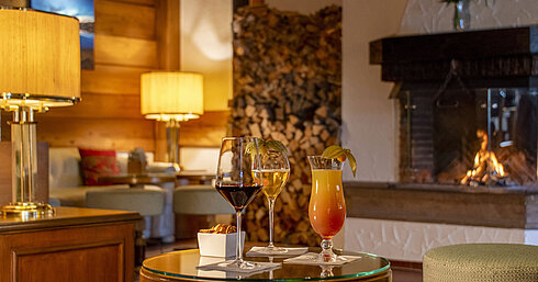 Vino, cerveza y cóctel en una mesa frente a la chimenea del bar del Hotel Maritim Titisee