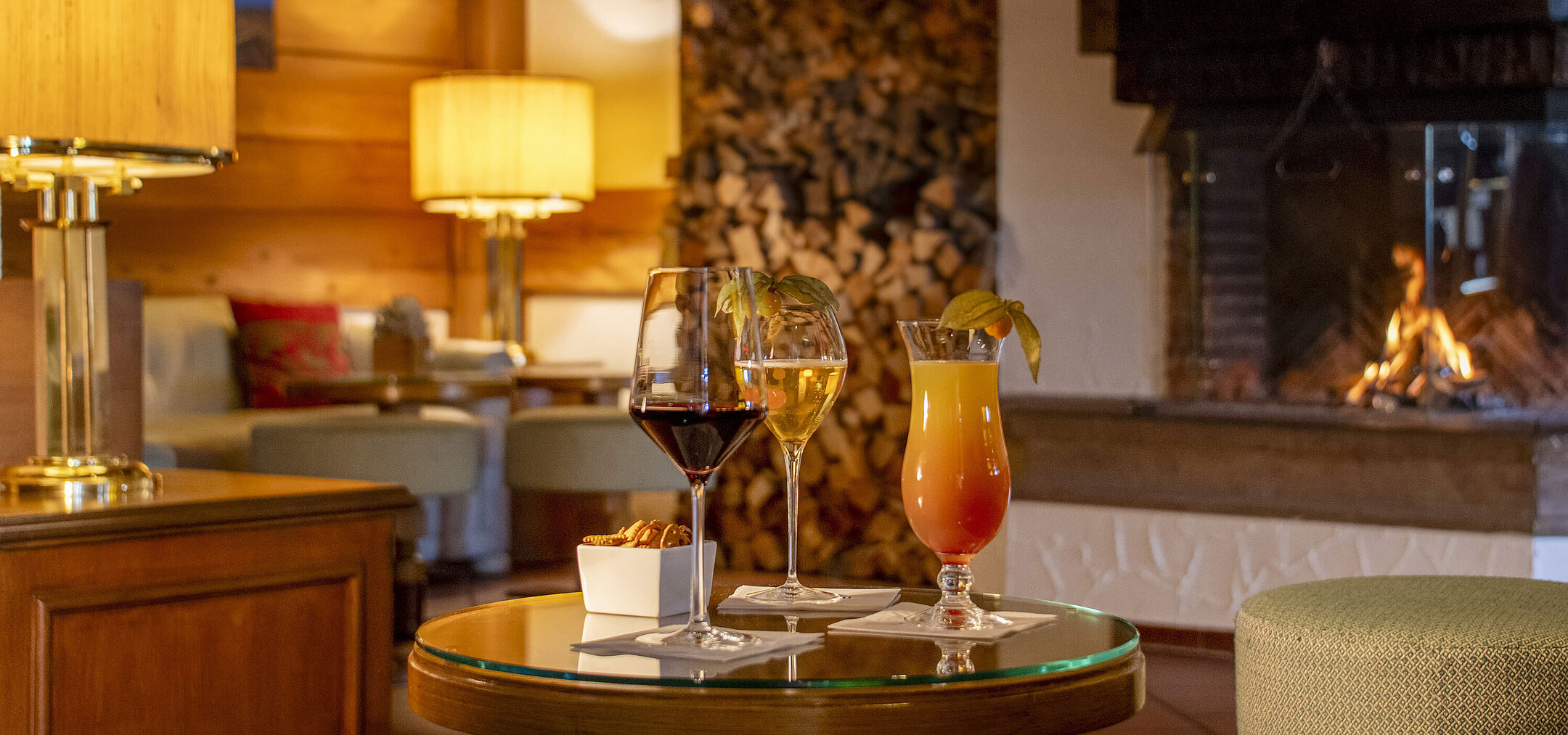 Vino, cerveza y cóctel en una mesa frente a la chimenea del bar del Hotel Maritim Titisee