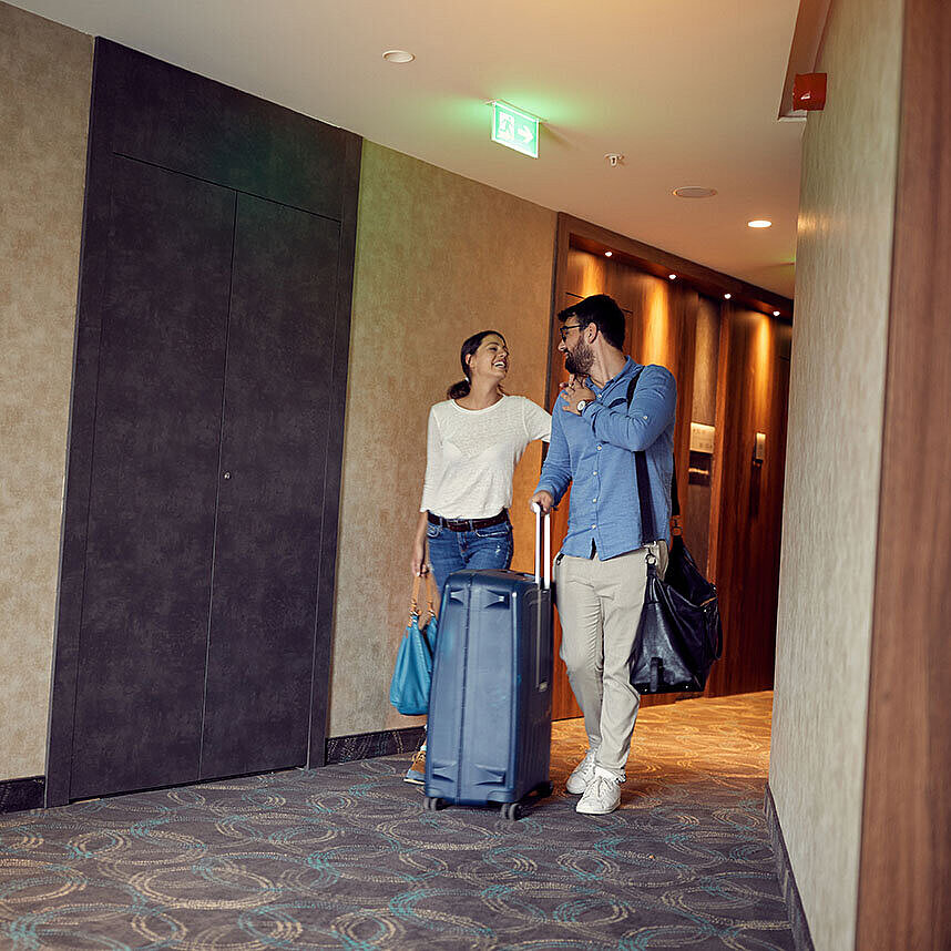 Pareja con maletas en el pasillo del hotel disfrutando su estancia