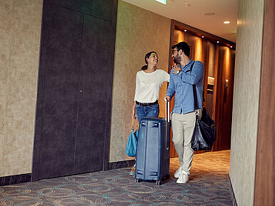 Couple with luggage in hotel corridor looking forward to their stay