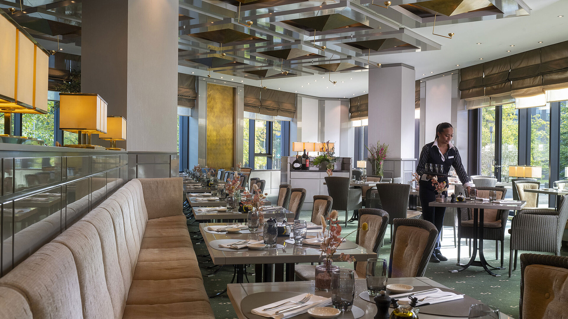 Restaurante elegante en el Hotel Maritim Düsseldorf con mesas preparadas y una camarera.