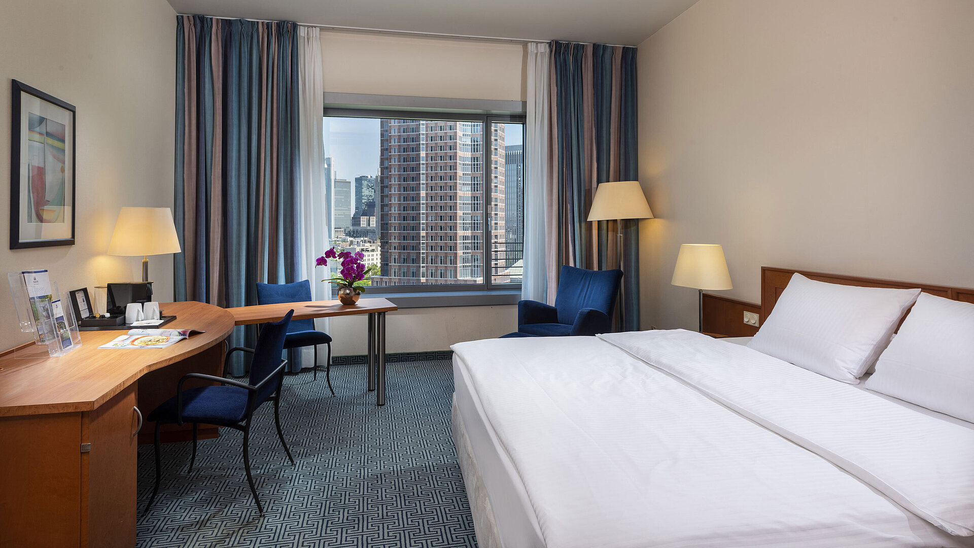Camera Superior del Maritim Hotel Frankfurt con letto matrimoniale, scrivania e vista sullo skyline di Francoforte.
