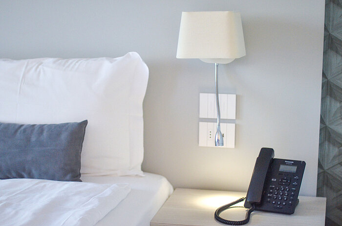 Dettaglio del comodino al Maritim Resort Calabria con telefono e lampada da lettura a LED