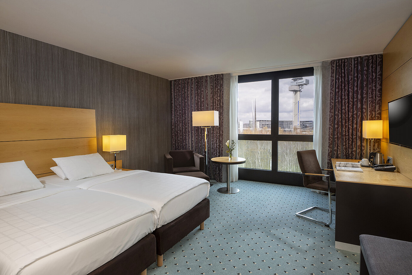Habitación clásica en el Maritim Hotel Düsseldorf con cama doble, escritorio y ventana panorámica con vistas al entorno.