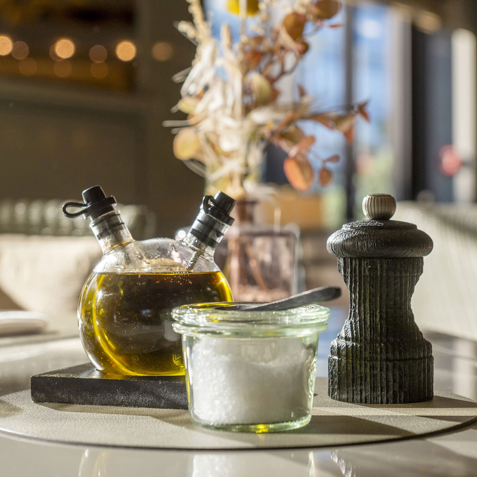 Gros plan sur une table dressée au Maritim Hotel Düsseldorf avec huile d'olive, sel et moulin à poivre.