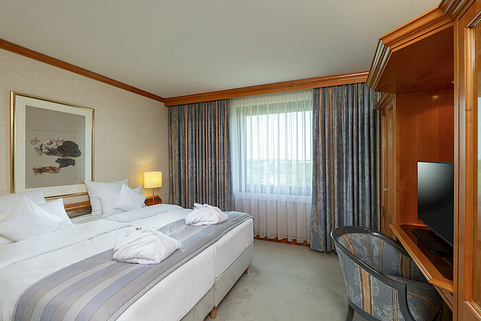 Habitación doble luminosa en Maritim Hotel Hannover con cama cómoda y escritorio.