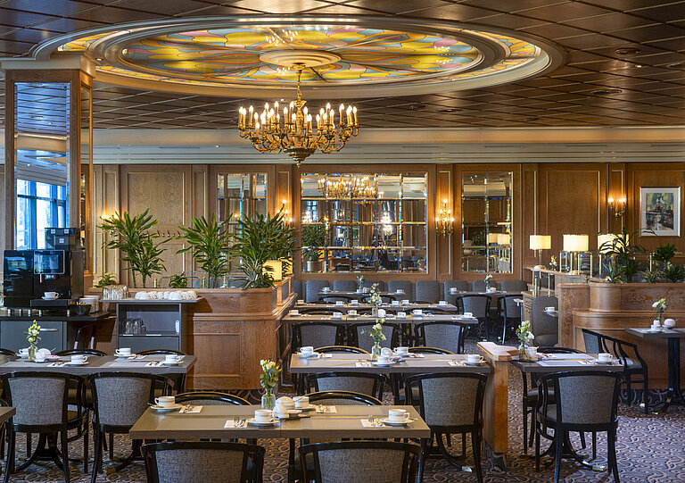 Stylish restaurant at Maritim Hotel Hannover with chandelier and floral glass ceiling.