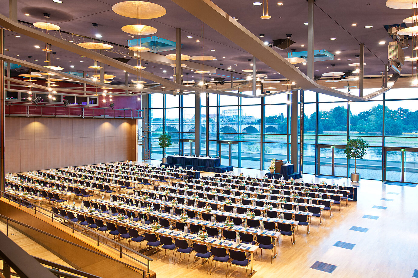 Gran sala de conferencias del Maritim Hotel Dresde con filas de sillas azules y vista al río Elba.