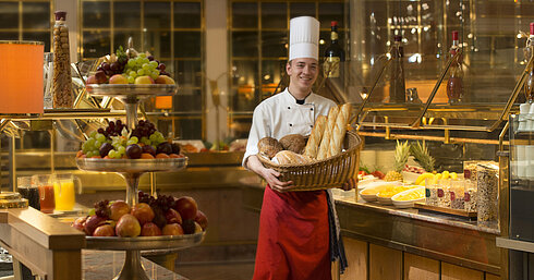 Rôtisserie Restaurant Baker with basket of bread at breakfast buffet at Maritim Hotel Stuttgart, surrounded by fresh fruit