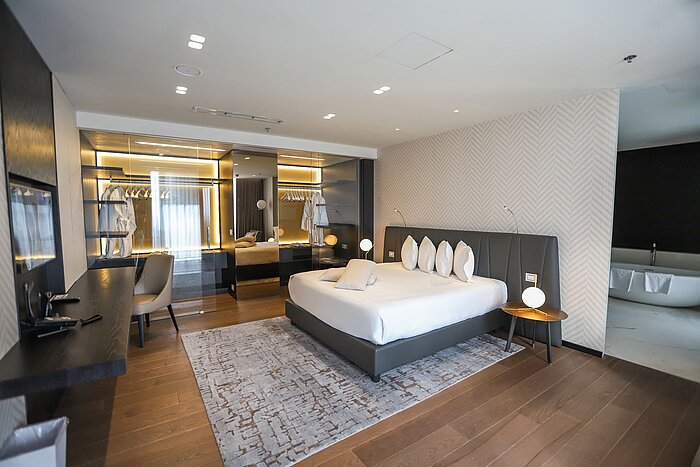 Camera di design con letto ampio, parete a specchio e zona guardaroba al Maritim Hotel Plaza Tirana