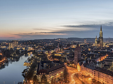 Night panorama of Ulm with illuminated Minster and Danube, captured at blue hour.