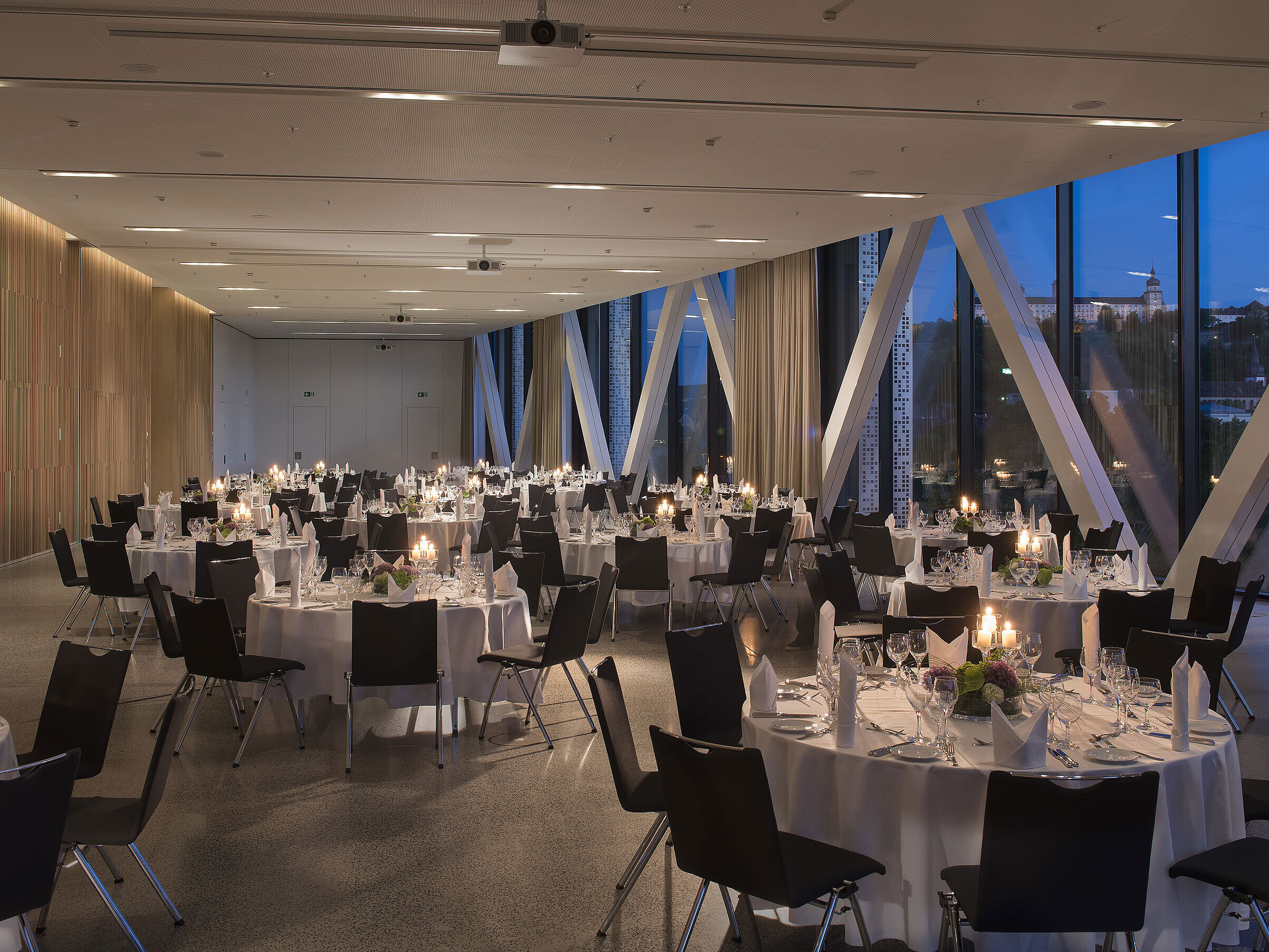 Elegante sala de eventos del Maritim Hotel Würzburg con mesas redondas y vista a la fortaleza