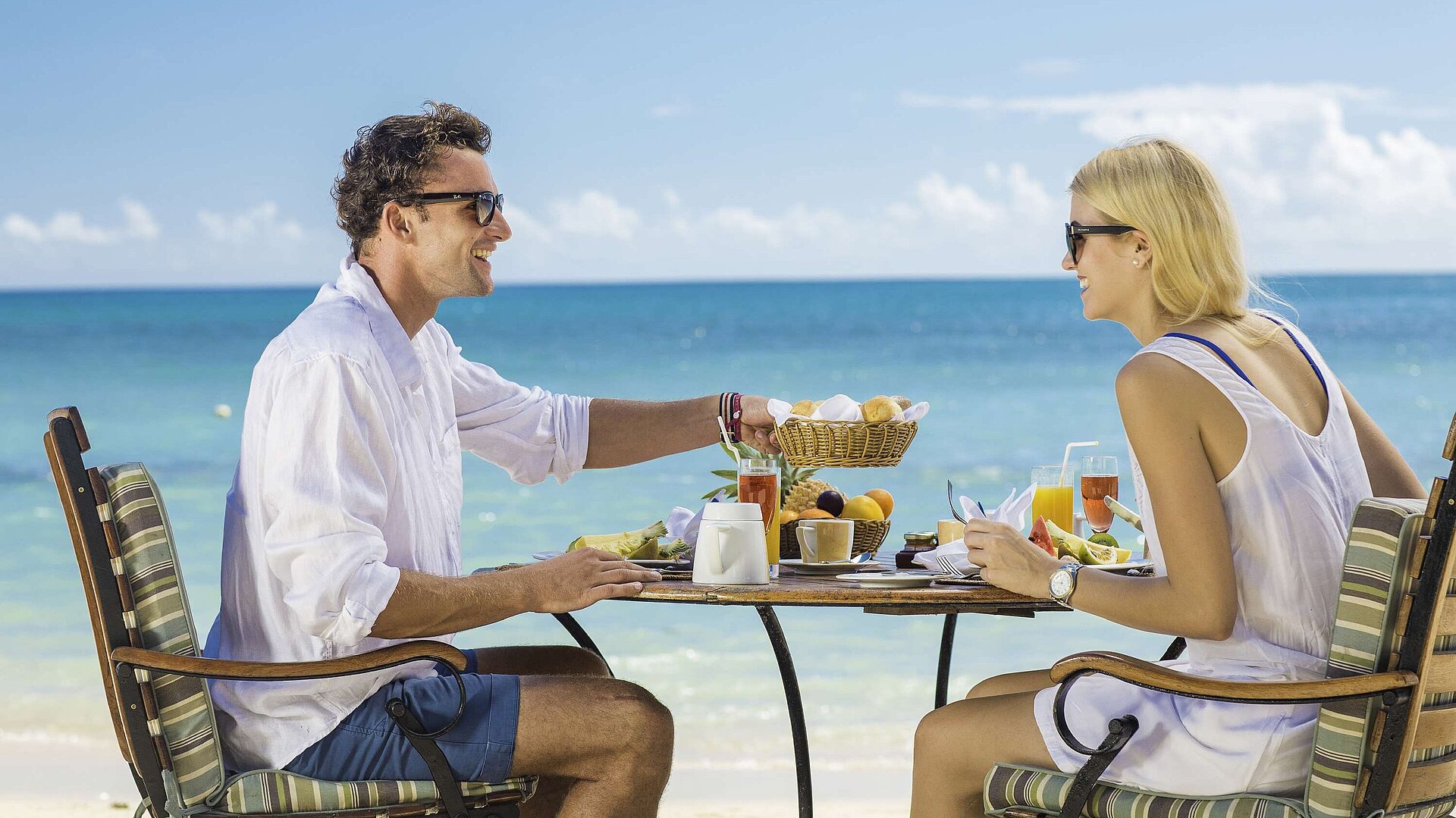 Breakfast on the beach Couple enjoying a relaxed beach breakfast with sea view on a sunny holiday