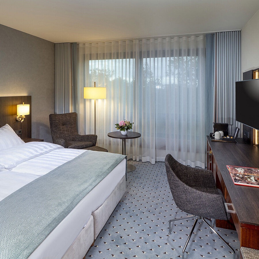 Chambre double Superior moderne à l’hôtel Maritim de Brême avec coin salon, bureau et grande fenêtre lumineuse.