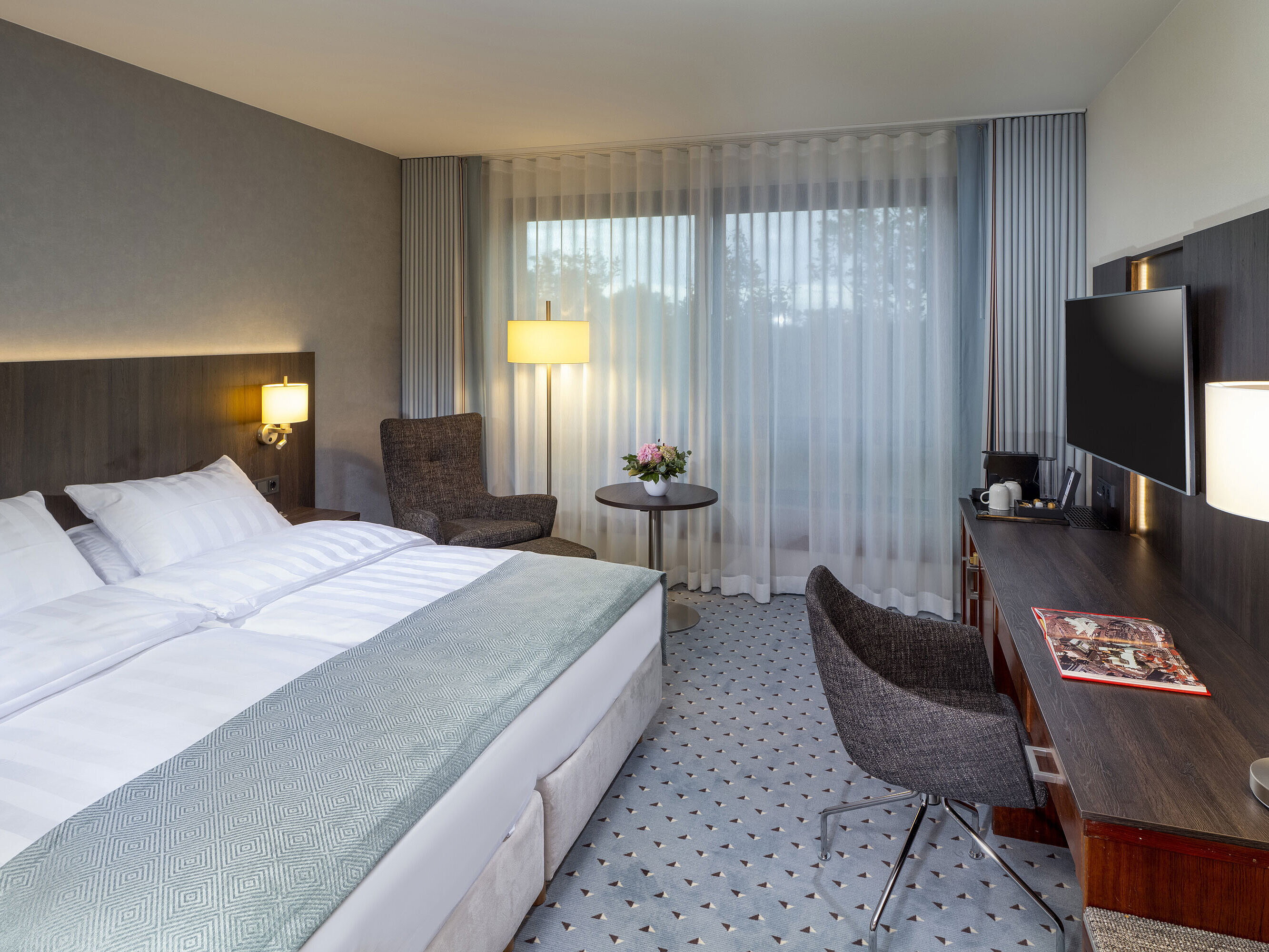 Modern Superior double room at Maritim Hotel Bremen with seating area, desk, and large window for natural light.
