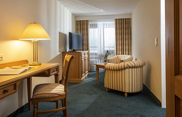 Zona giorno con TV, scrivania e poltrone comode al Maritim Hotel Titisee