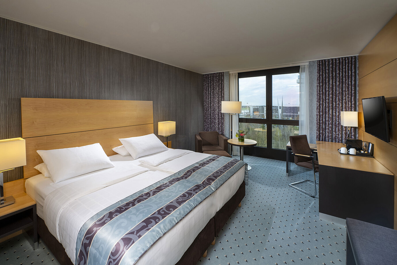 Habitación superior moderna en el Maritim Hotel Düsseldorf con cama grande, escritorio y vistas a la ciudad.