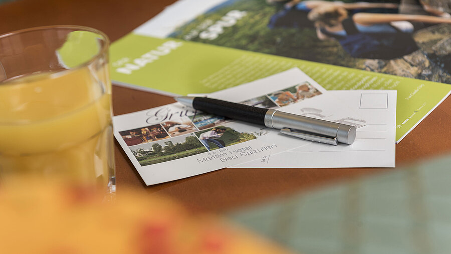 Table with postcard from Maritim Hotel Bad Salzuflen, pen, juice and brochure