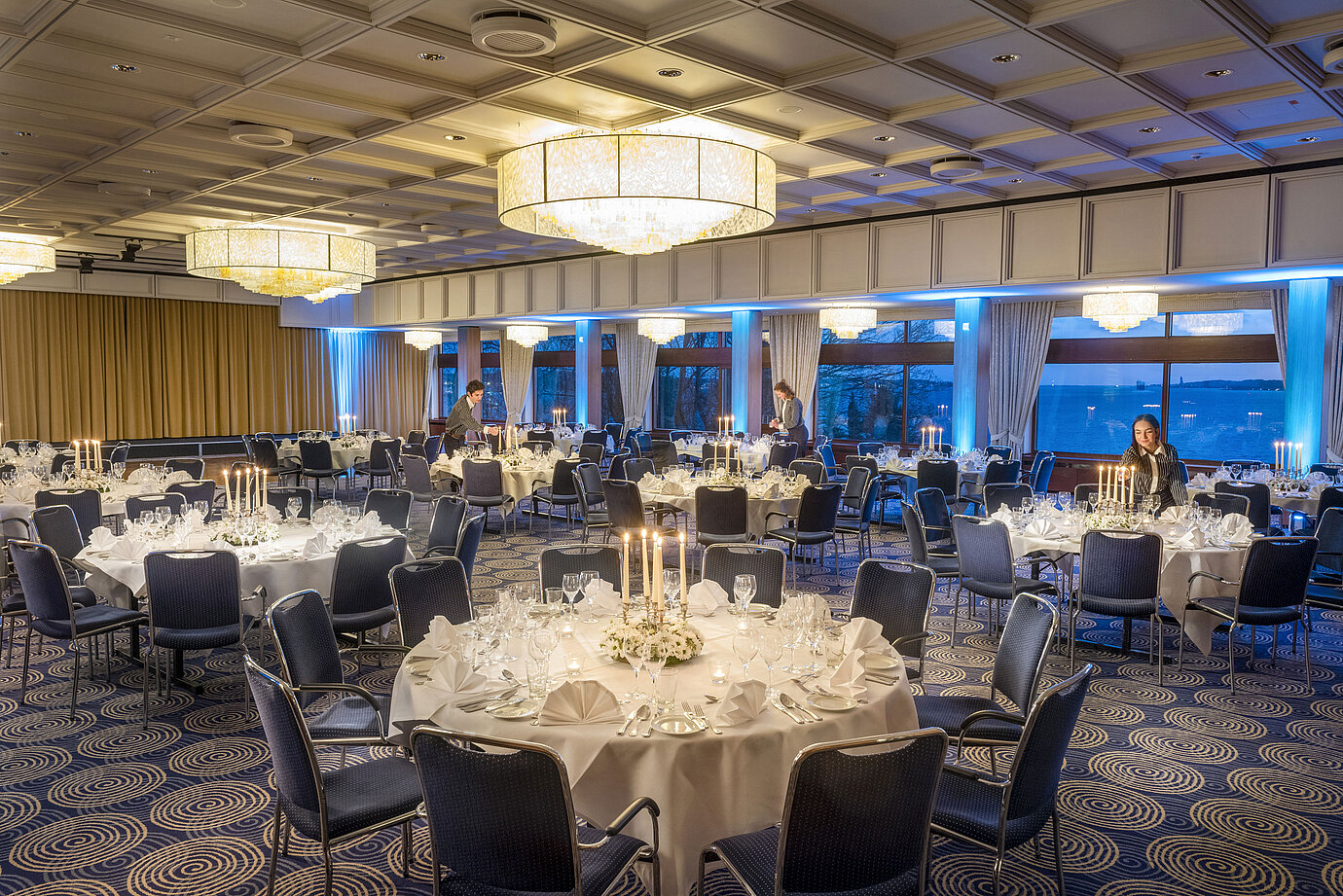 Sala Maritim del Maritim Hotel Kiel, tavoli imbanditi a lume di candela, ambiente elegante, personale che prepara l'evento.