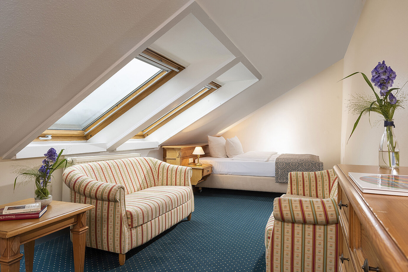 Camera accogliente in mansarda con lucernari, divano e poltrona al Maritim Hotel Titisee