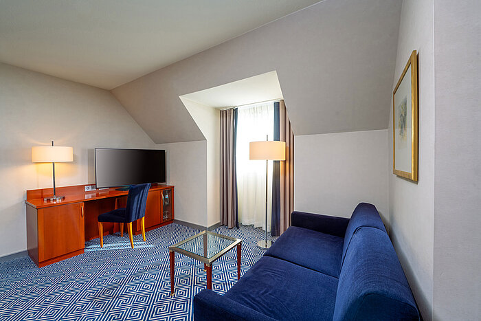 Living area of the Classic Family room at Maritim Hotel Würzburg with sofa bed and desk