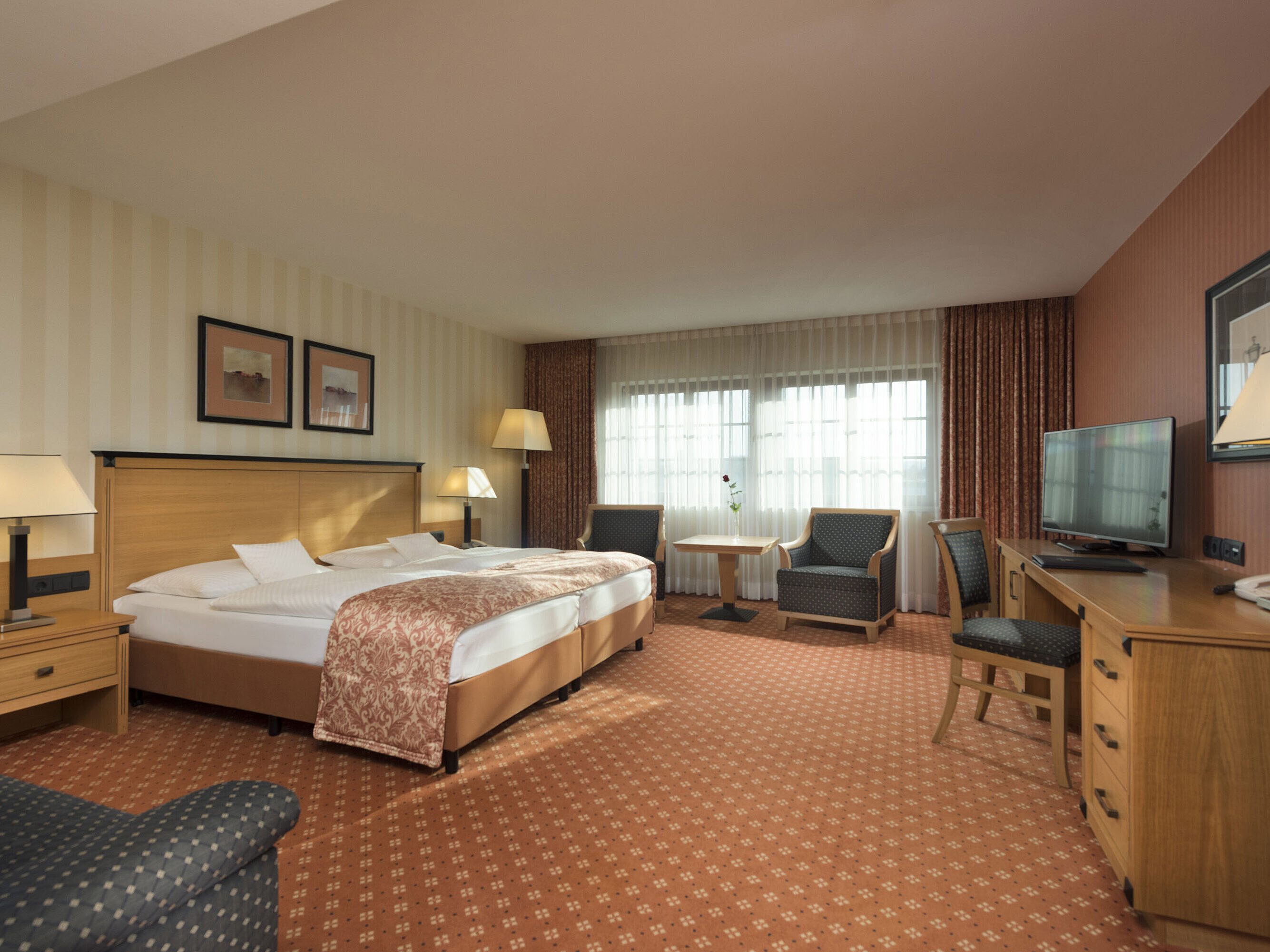 Chambre classique à l'hôtel Maritim de Dresde avec lit double, coin salon et décor classique.