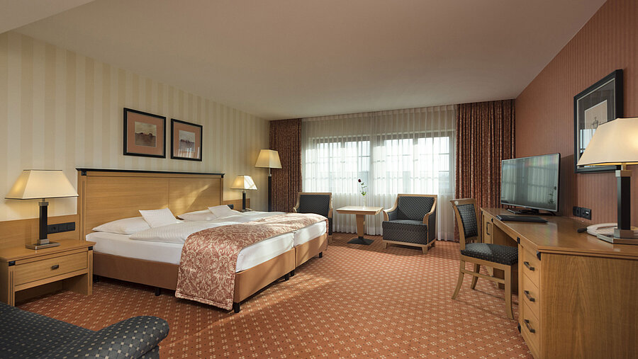 Chambre classique à l'hôtel Maritim de Dresde avec lit double, coin salon et décor classique.