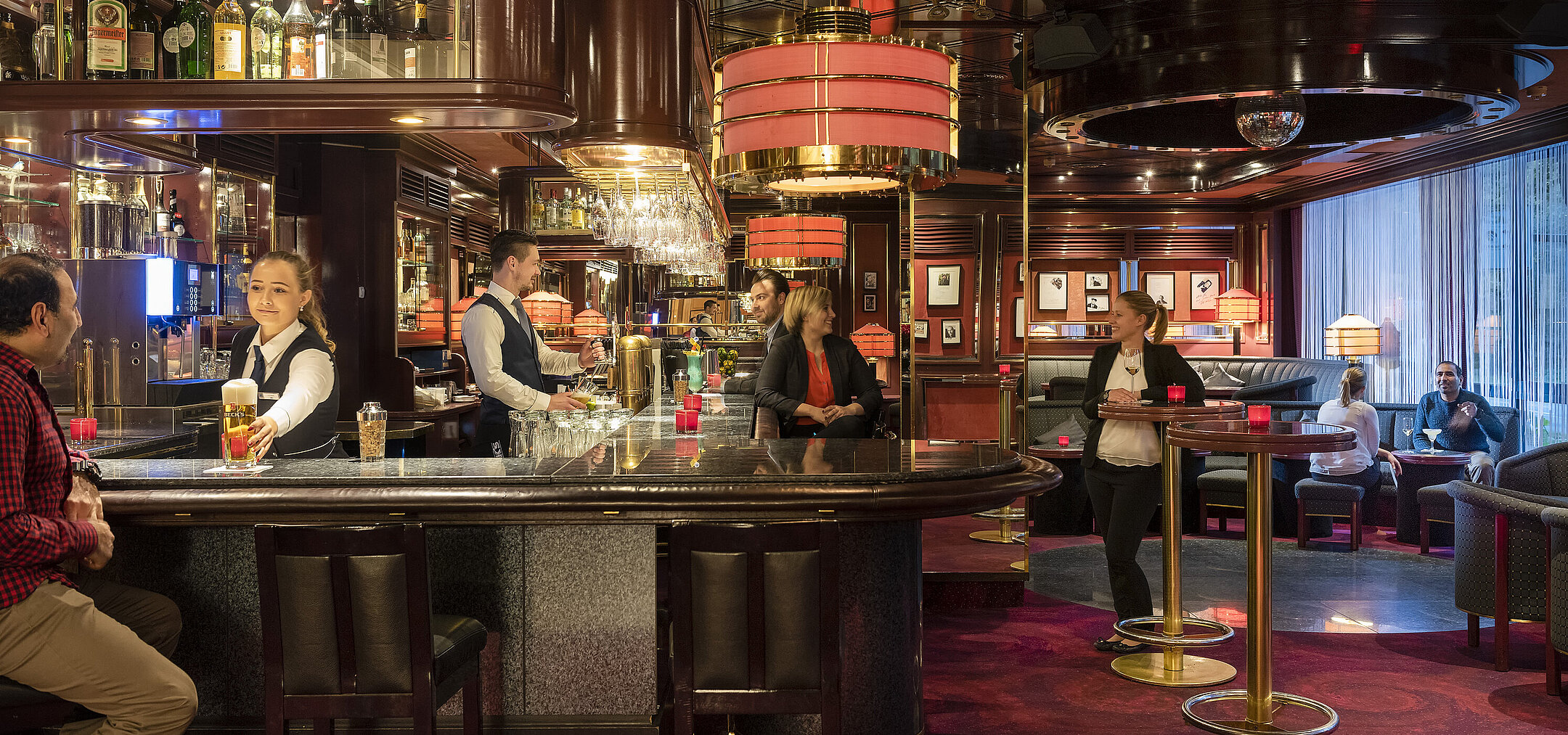 Los huéspedes disfrutan de bebidas y un ambiente relajado en la elegante bar del Hotel Bremen, atendidos por personal amable.