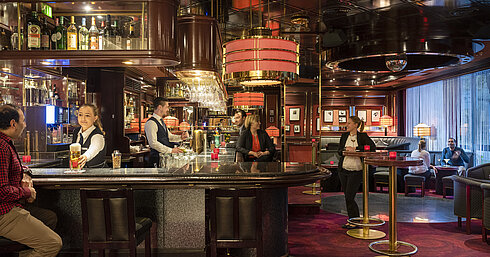 Guests enjoy drinks and a relaxed atmosphere in the stylish bar of Maritim Hotel Bremen, served by friendly staff.