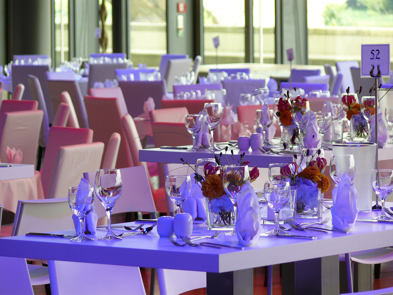 Primer plano de mesas elegantemente dispuestas con arreglos florales en la sala de eventos del Maritim Hotel Dresden.