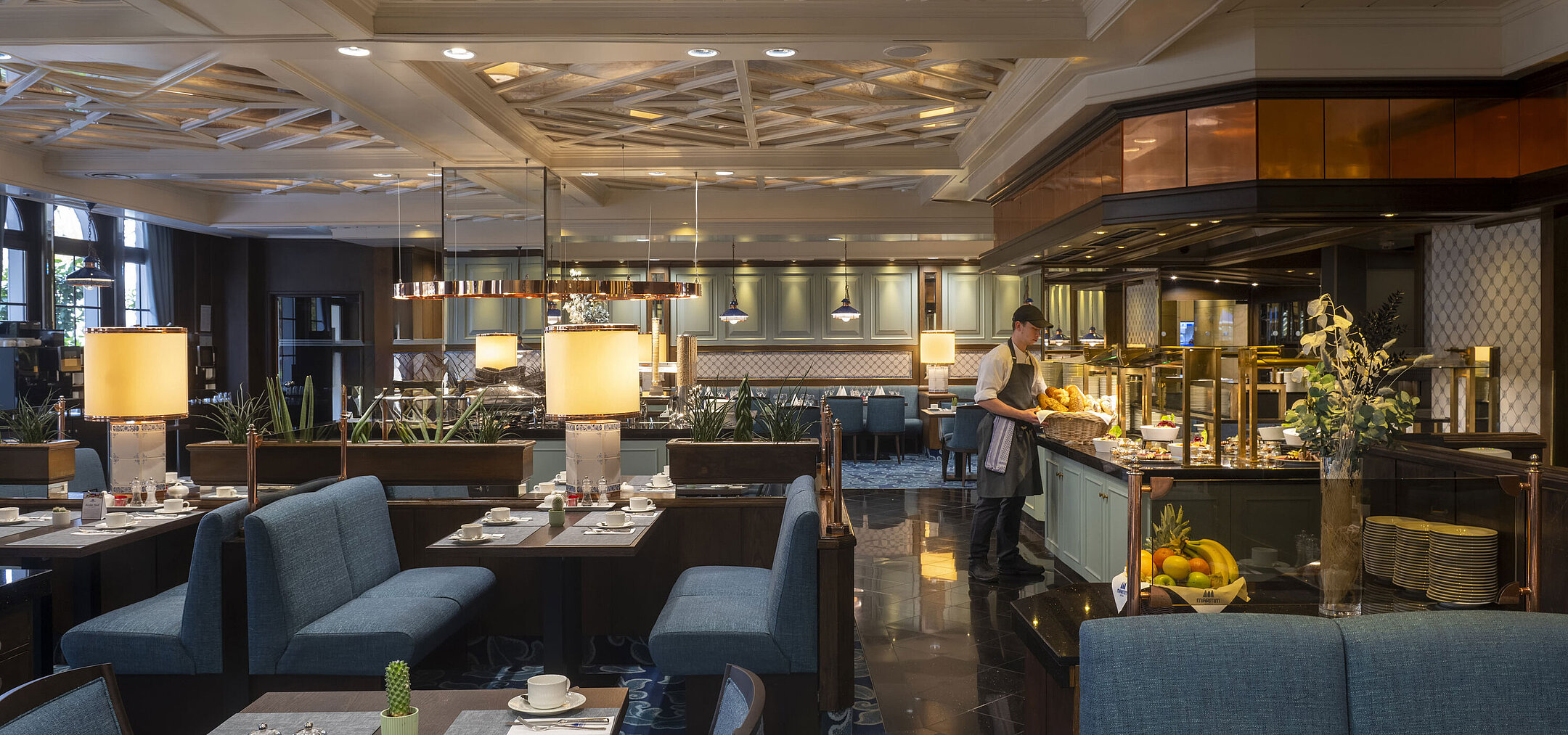 Restaurante del hotel Maritim Darmstadt con mesas preparadas, área de buffet e iluminación elegante bajo un techo artístico.