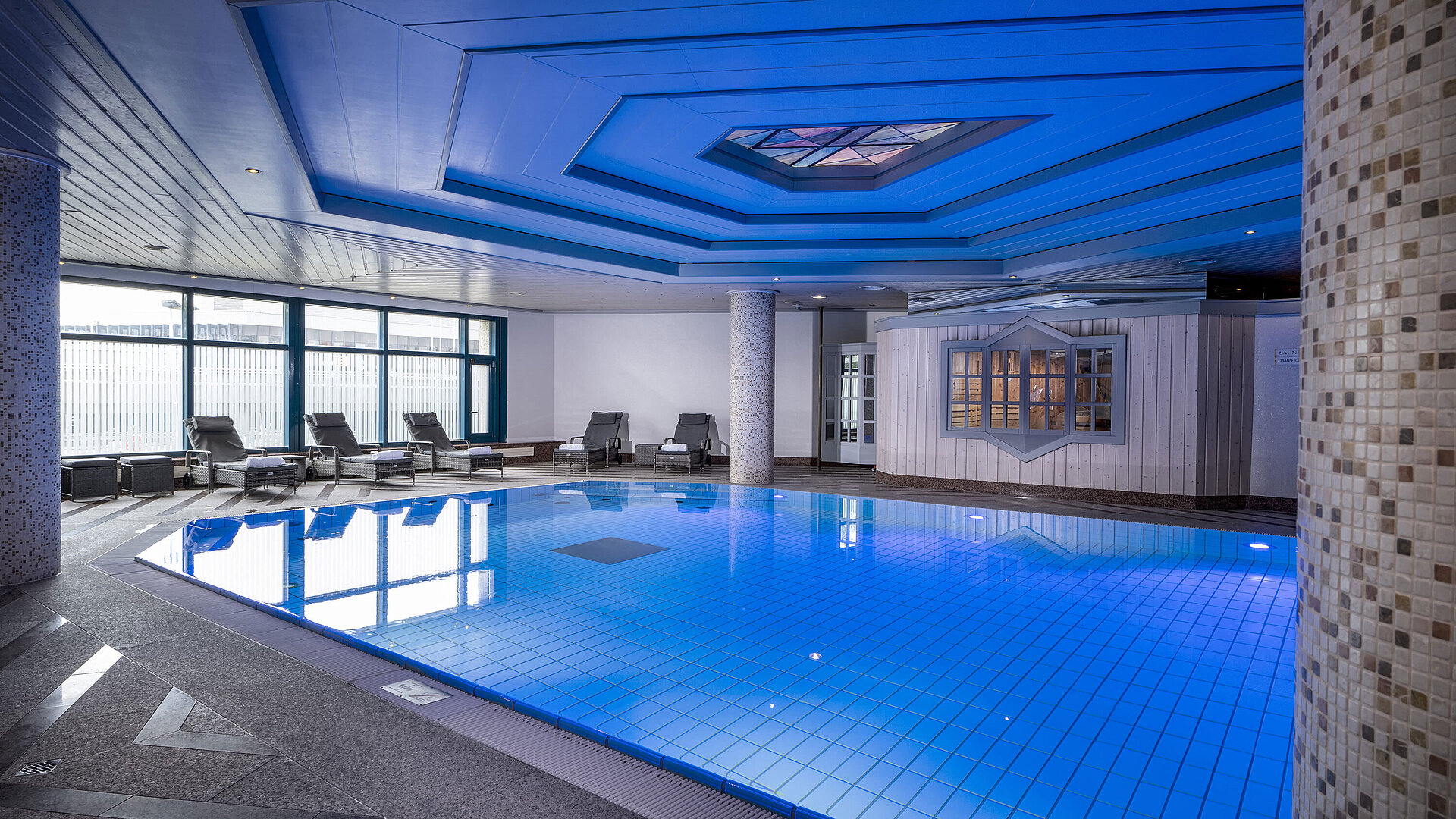 Piscina Piscina cubierta en Maritim Hotel Hannover con tumbonas e iluminación moderna.