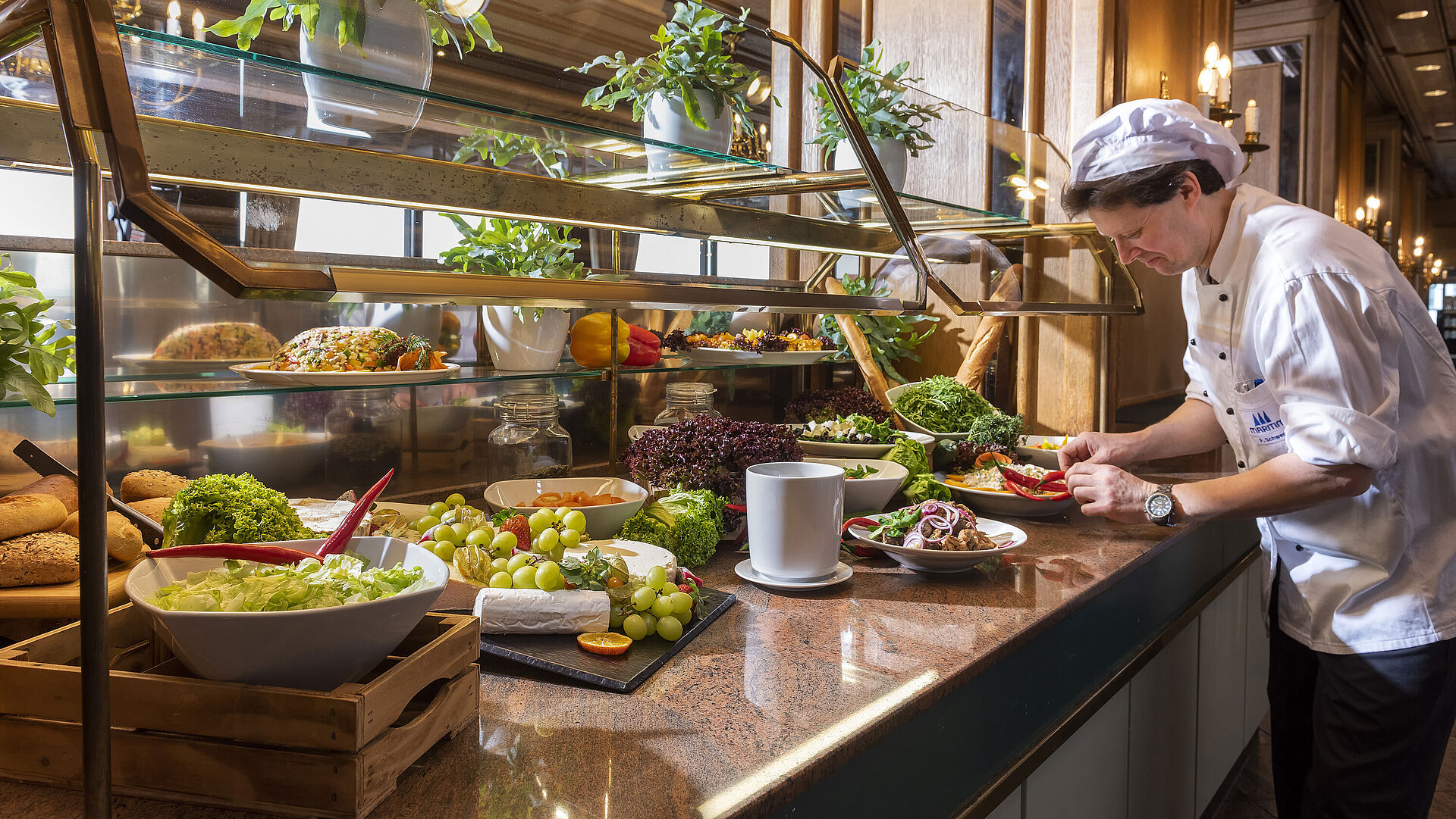 El chef prepara un buffet de ensaladas y verduras frescas en el restaurante del Maritim Hotel Travemünde
