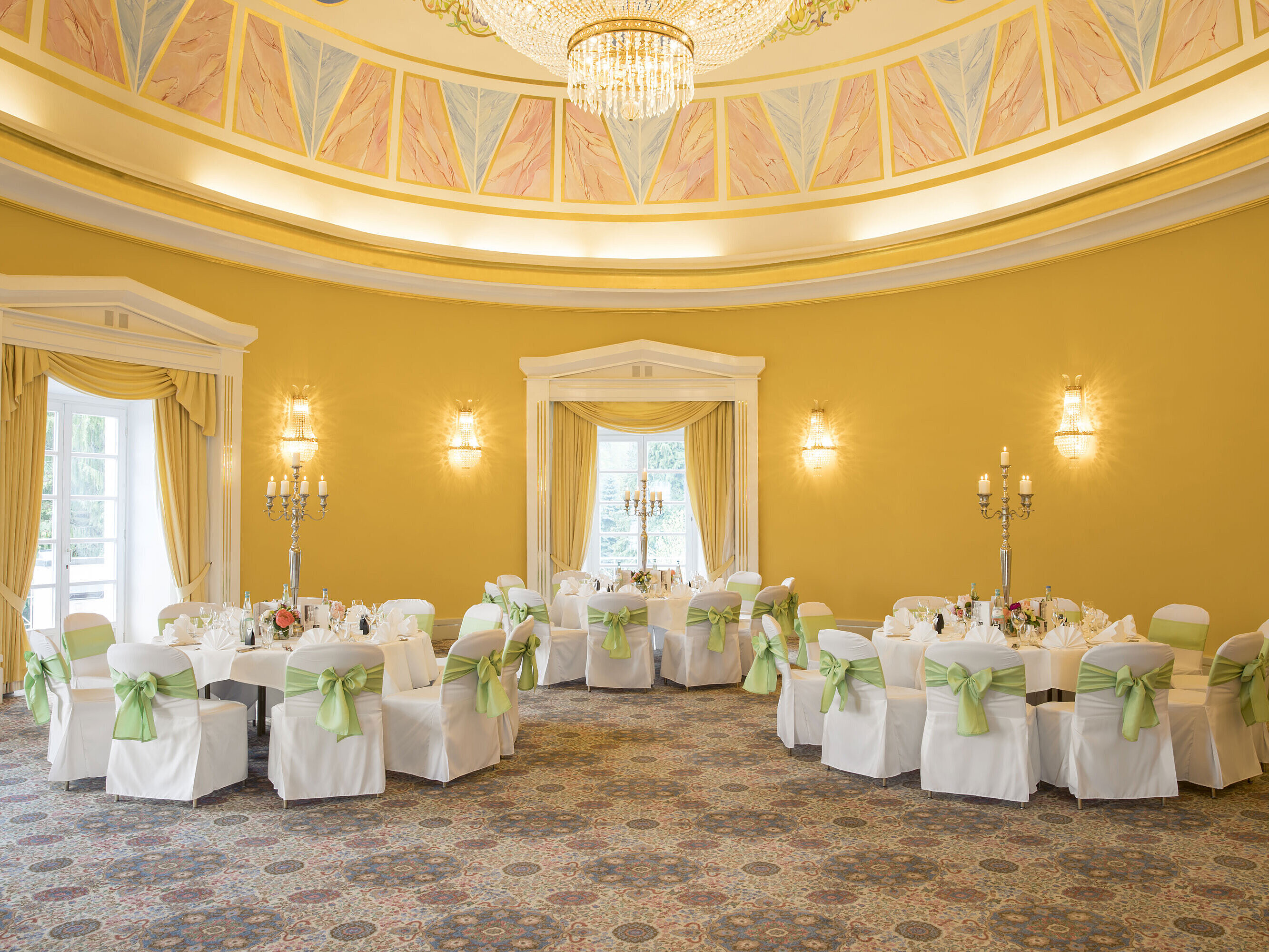Salón elegante con paredes amarillas, mesas redondas y candelabros en el Maritim Hotel Bad Wildungen