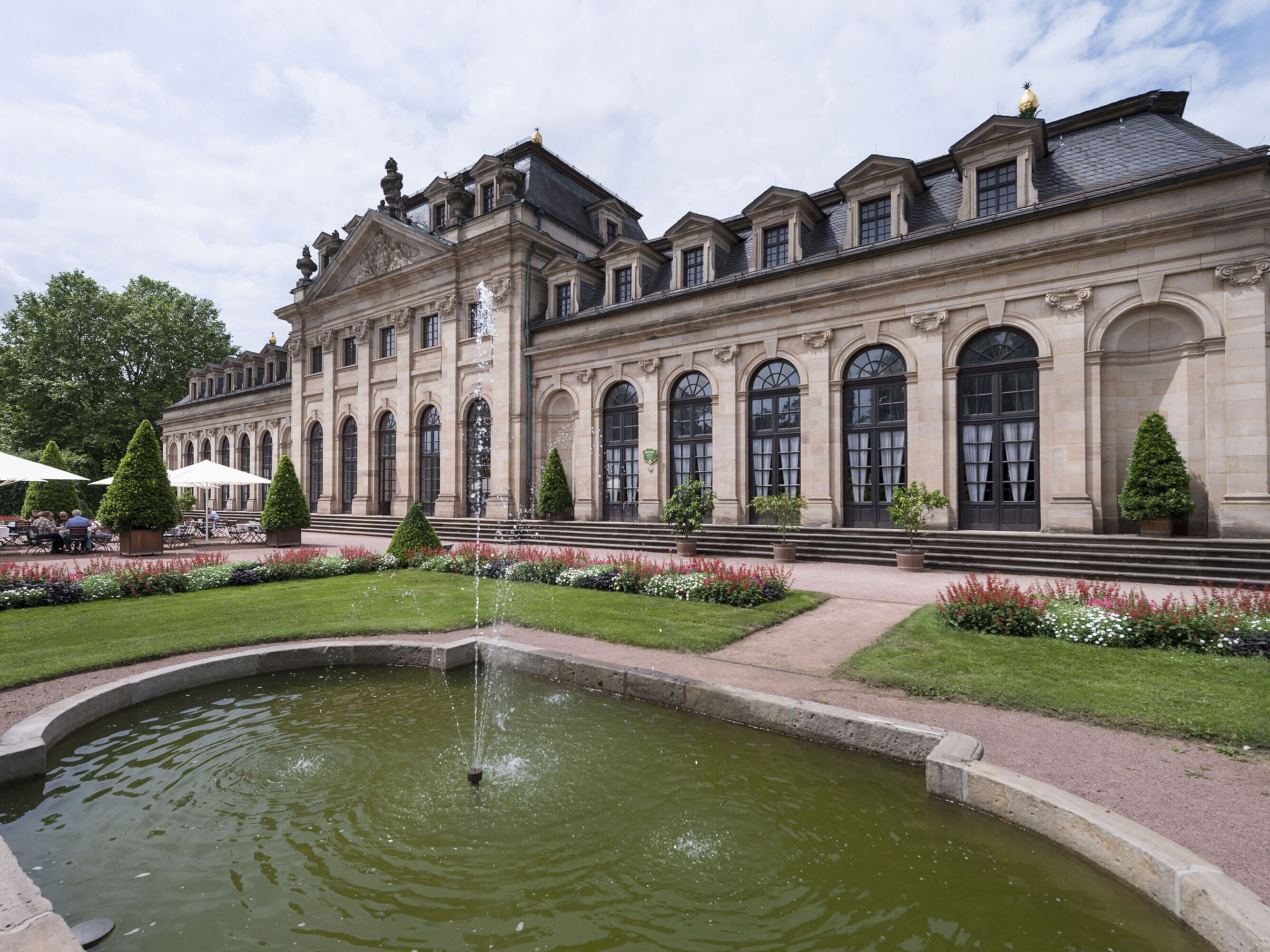 L’Orangerie barocca di Fulda con terrazza, giardino curato e fontana storica in primo piano.