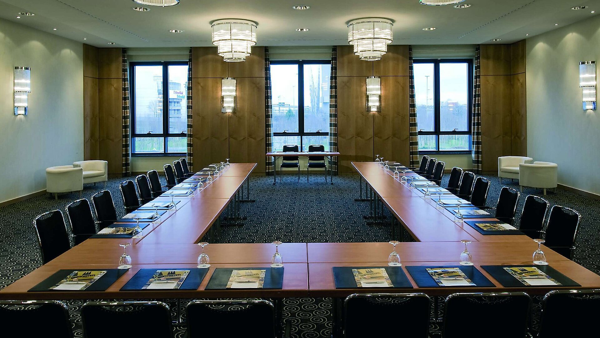 Sala de conferencias moderna en el Maritim Düsseldorf con disposición en forma de U, grandes ventanas e iluminación elegante.