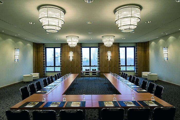 Sala de conferencias moderna en el Maritim Düsseldorf con disposición en forma de U, grandes ventanas e iluminación elegante.