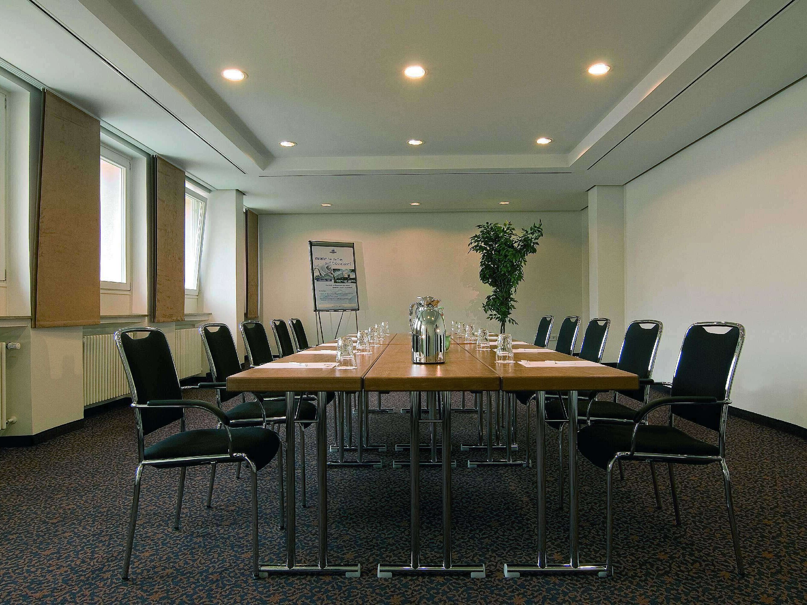 Luminoso sala riunioni al Maritim Hotel Fulda con attrezzature moderne e tavolo conferenze.