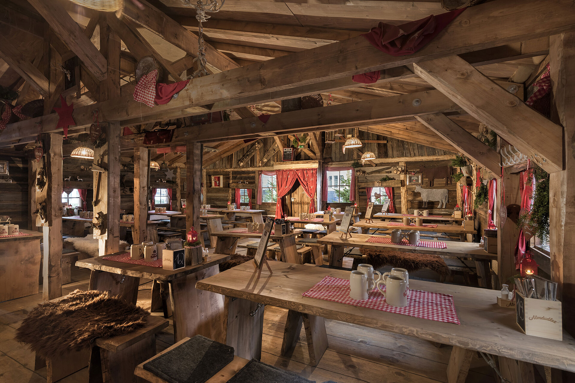 Almhütte Warm interior with wooden tables, red curtains and rustic decor at Maritim Alm Stuttgart