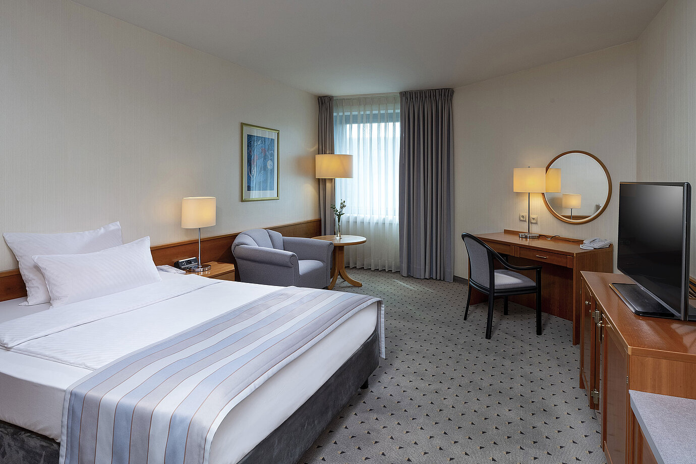 Habitación Classic acogedora con cama grande, escritorio, TV y decoración elegante en el Maritim Hotel Hannover.