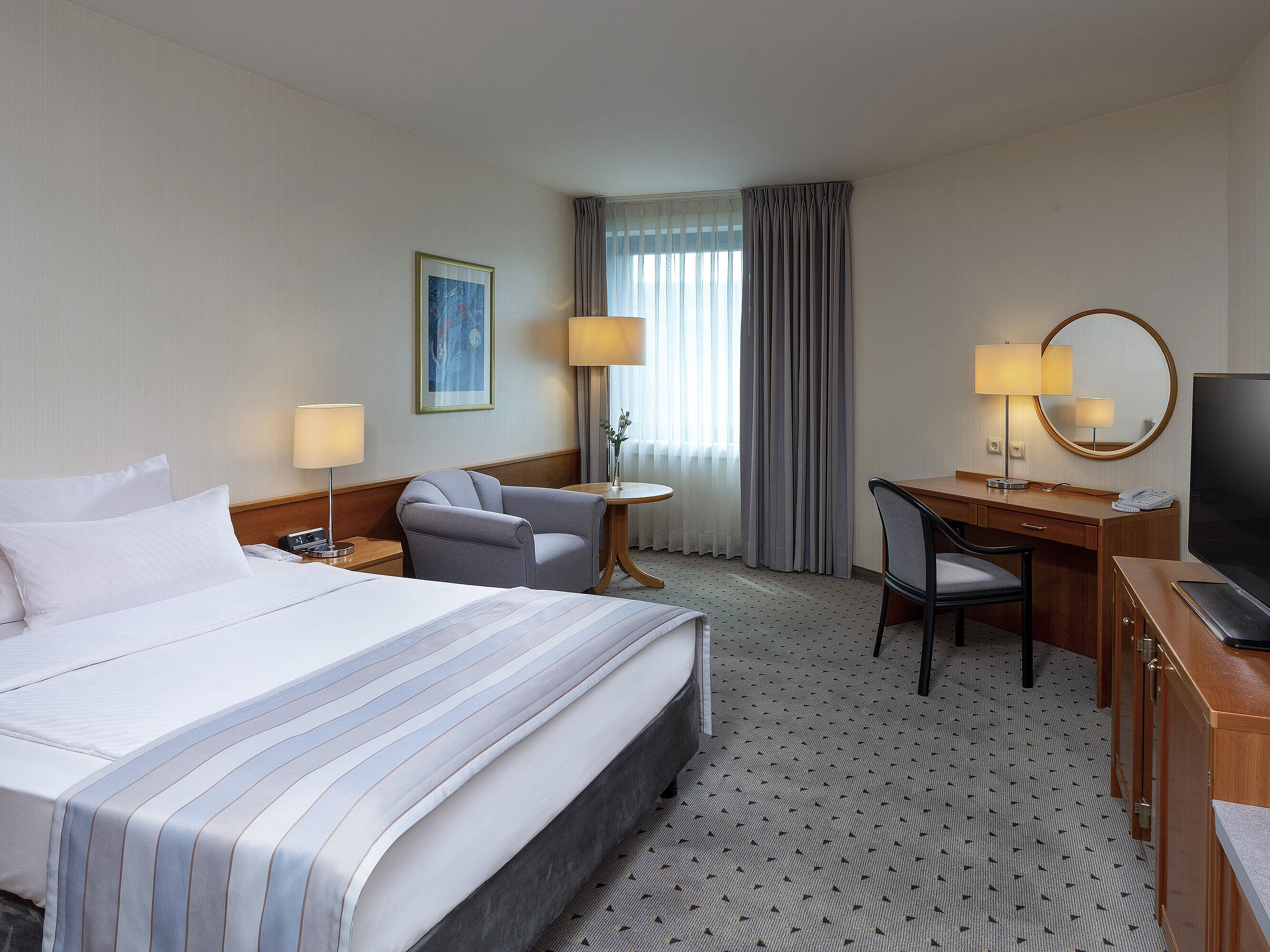 Habitación Classic acogedora con cama grande, escritorio, TV y decoración elegante en el Maritim Hotel Hannover.