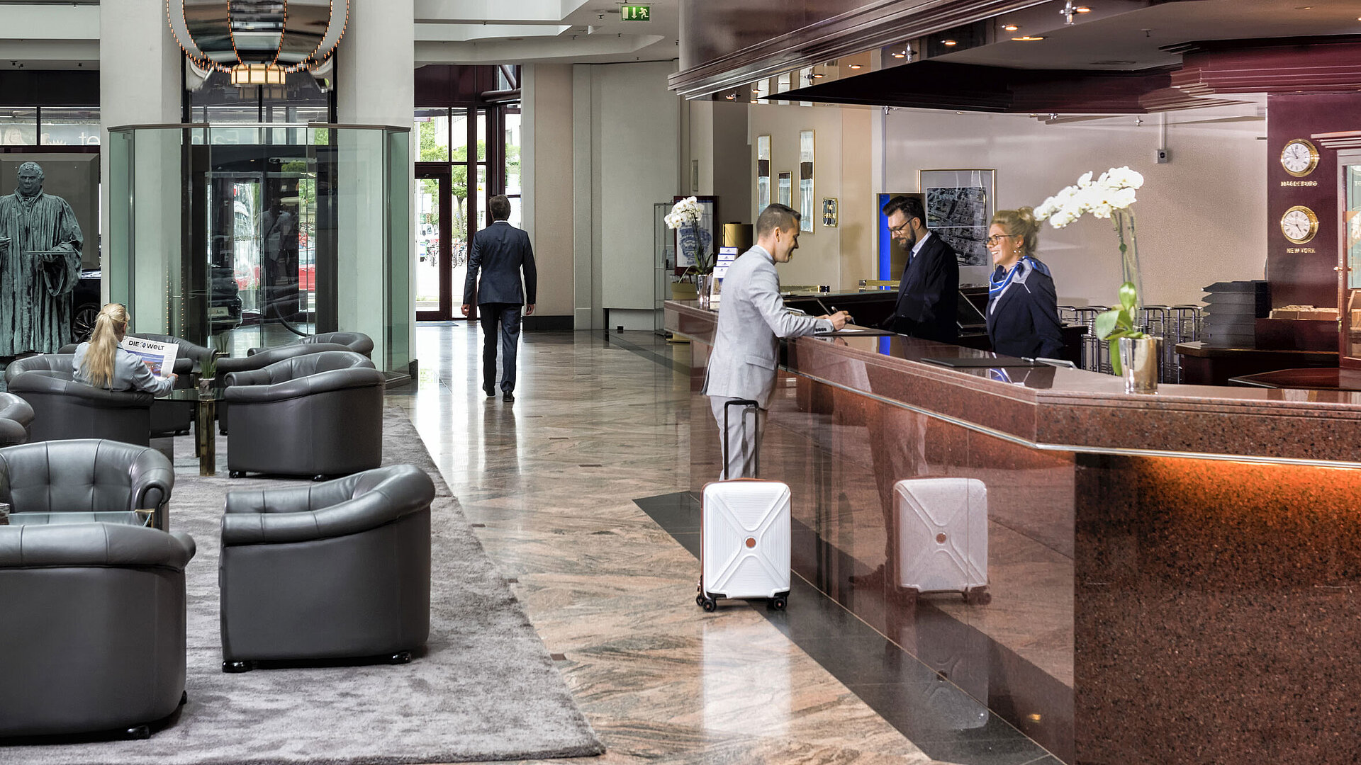 A guest checks in at the reception and is served by a friendly staff member.