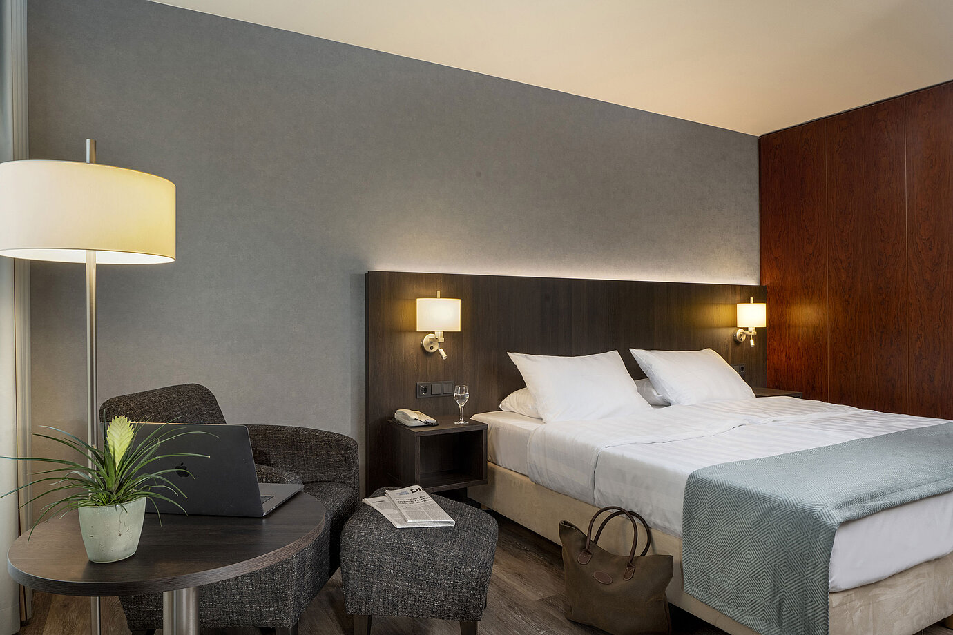 Modern double room at Maritim Hotel Bremen with cozy seating area, side table, vase, and inviting bed.