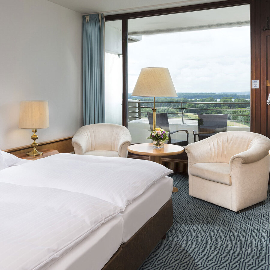 Chambre double avec coin salon, bureau et balcon sur paysage verdoyant à Travemünde