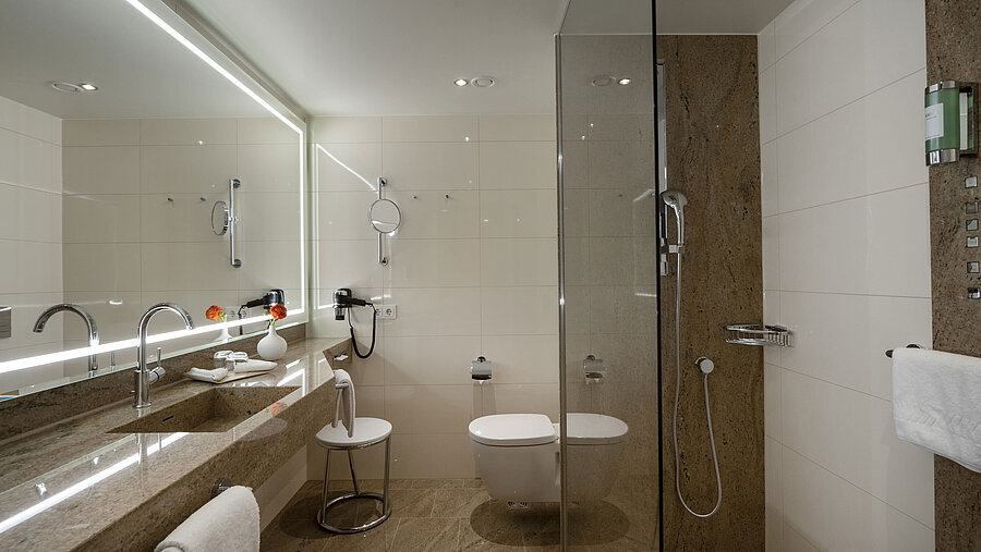 Modern bathroom at Maritim Hotel Ingolstadt with glass shower, large mirror, and stylish design.