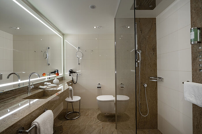 Modern bathroom at Maritim Hotel Ingolstadt with glass shower, large mirror, and stylish design.