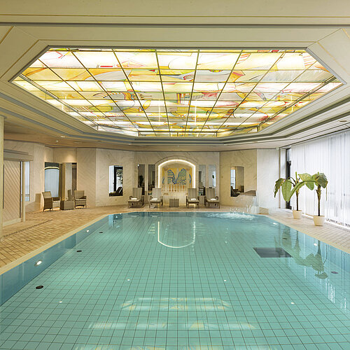 Piscine intérieure avec puits de lumière et chaises longues au Maritim Hotel Ulm