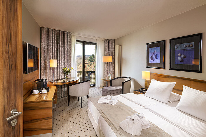 Habitación confort en el Maritim Hotel Bad Homburg con balcón, diseño luminoso y zona de estar acogedora.